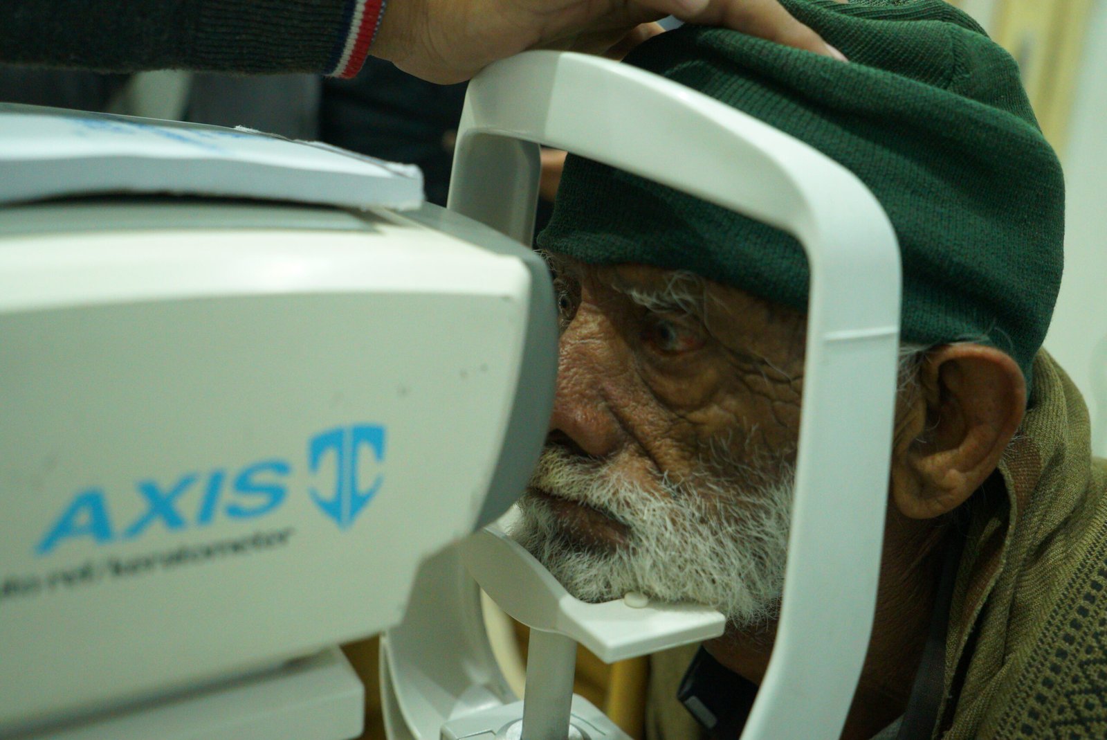 Elderly patient using the AXIS keratometer for eye diagnostics