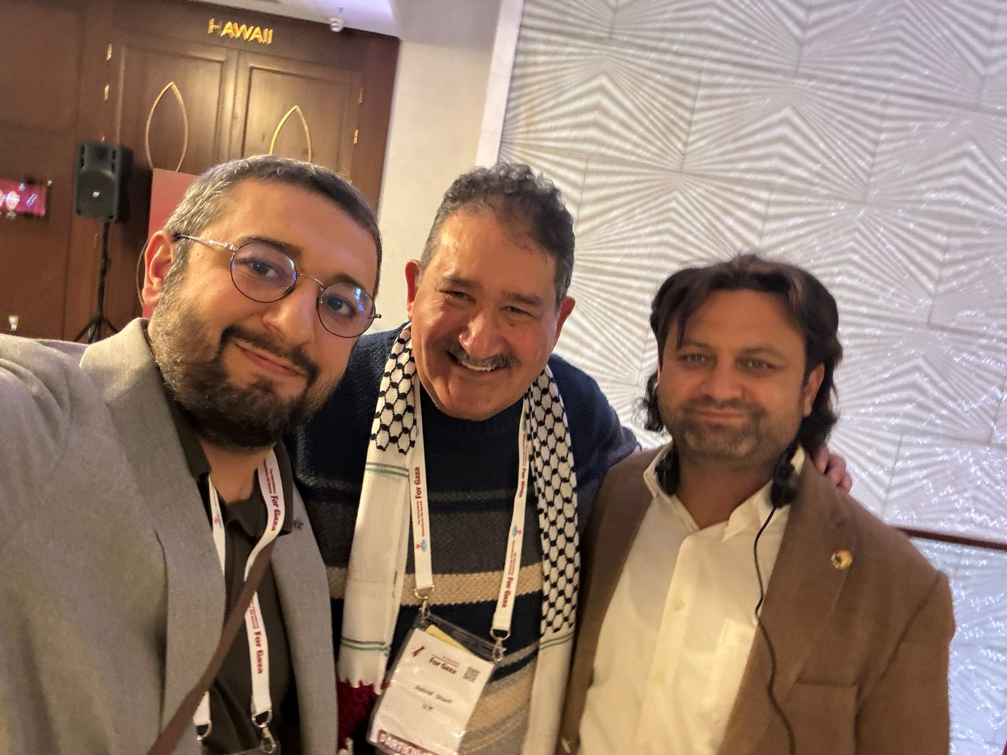 Gazian team members at conference showing commitment to Gaza relief. Three team members wearing 'For Gaza' lanyards, demonstrating unity and purpose.