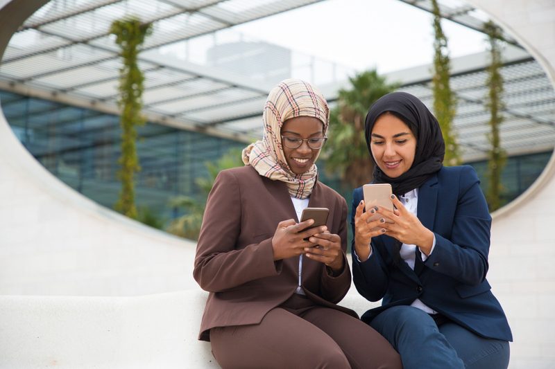 İki kadın akıllı telefon kullanıyor, HajiQ ekosisteminin bağlantılı dijital araçları